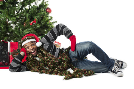 Portrait of a happy African American man lying on his side beside a Christmas tree, Model  Eddie...