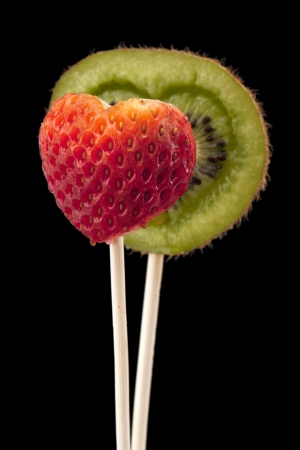 Close up image of a heart shaped kiwi and strawberry on dark backgroundの写真素材