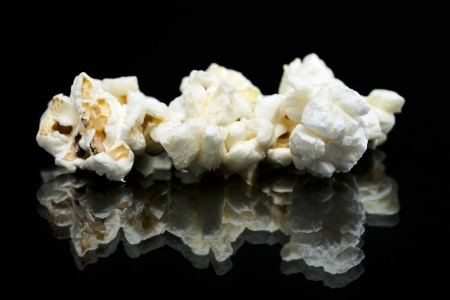 Tree pieces of popcorn isolated in a black background with reflectionの写真素材