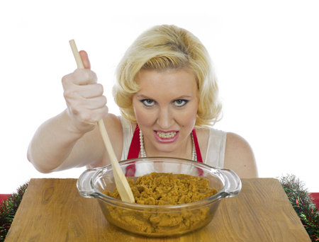 Young woman grinding teeth and mixing cookie paste against white backgroundの写真素材