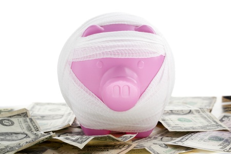 Close-up shot of a pink piggy bank wrapped in bandage on banknote.の写真素材