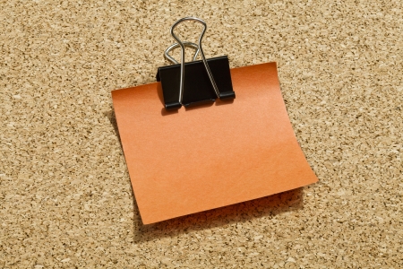 Image of orange adhesive paper with black paper clipの写真素材