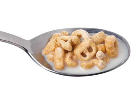 Close-up image of cereals with milk on the spoon over the white background