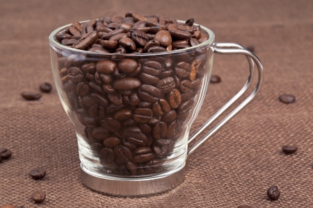 A pitcher of roasted coffee beans placed in a brown mat with few scattered beansの写真素材