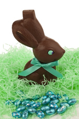 Close up image of chocolate rabbit and candies in green confetti against white backgroundの写真素材