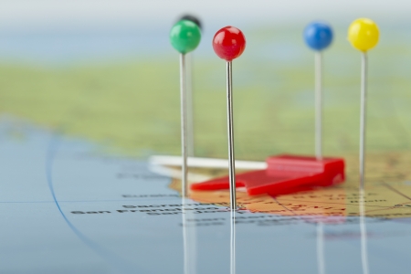 Horizontal image of a world map with colorful pins and a red flag lying on itの写真素材
