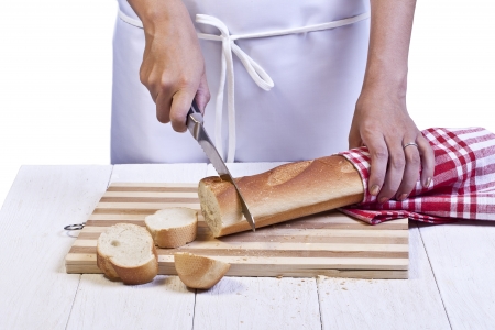 Baker wearing apron slicing a long baguette breadの写真素材