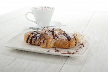 Image of chocolate flavor croissant with hot coffee on the side on a wooden tableの写真素材