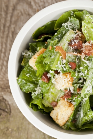 Closed up cropped bowl of caesar salad placed on top of a wooden tableの写真素材