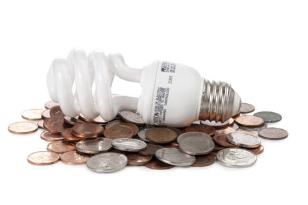 Close-up image of a light bulb lying on the coins against the white background