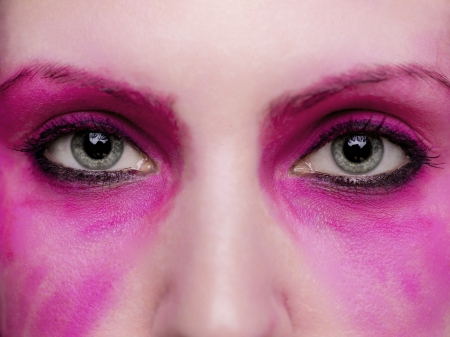A close up on a pair of eyes surrounded by hot pink make up.の写真素材