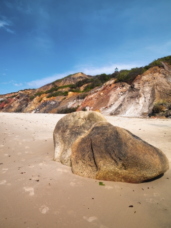 The tip of a lighthouse can be seen above a hill on a beach in Martha's Vineyard.の写真素材