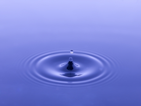 Single droplet on splashing blue waterの写真素材