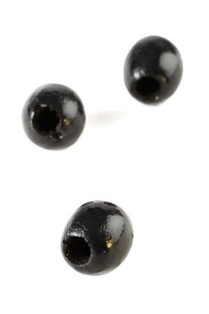 Portrait of three whole black olives on a white backgroundの写真素材