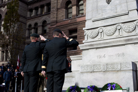Rear view of men in uniform saluting at war memorial.