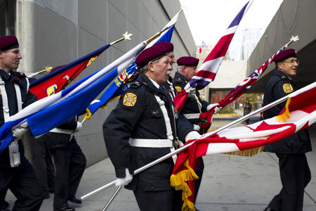 Side view of marching band of senior men in uniform holding flags.