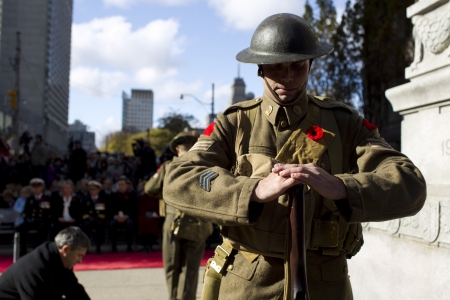 View of a mid adult man in military uniform with gun with people in background.のeditorial素材