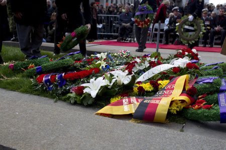 View of funeral flowers arranged at war memorial with people in background.