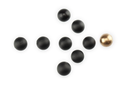 Image of black marbles forming arrow hitting the golden arrow against the white surfaceの写真素材