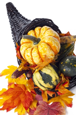 A collection of a colorful assortment of gourds and leaves in a dark wicker cornucopia.の写真素材