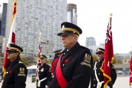 Image of a senior citizen in military uniform while people standing in background wearing military uniform and holding flag.のeditorial素材