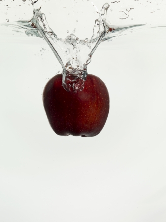 Close up image of apple dropping on clear water against white backgroundの写真素材