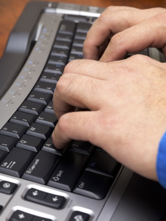 Close-up cropped image of human hands typing on black keyboard.の写真素材