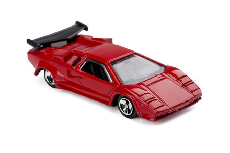 Image of red classic model toy car parked on a white surface