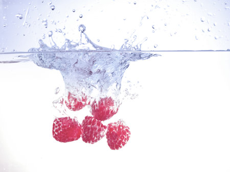 Raspberries drop into the waterの写真素材