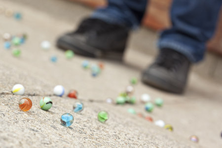 Scattered marbles with cropped image of standing man on the ground