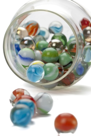 Close-up image of several marbles spilled on the jar isolated on a white backgroundの写真素材