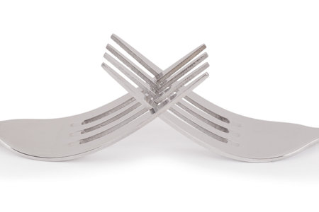 Close-up shot of two forks connected to each other over the white backgroundの写真素材