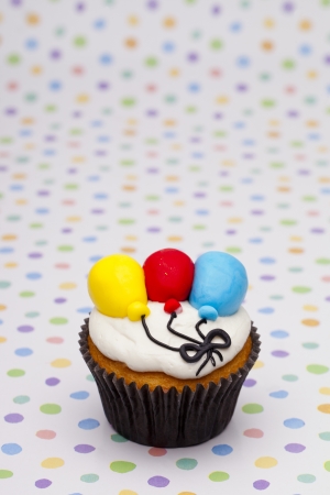 Close-up shot of cupcake with multi colored balloons  over polka dots background.の写真素材