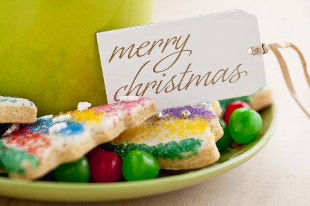 A plate of a cup of coffee with cookies, candies and a Christmas greetingの写真素材