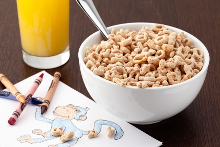 Bowl of cereal and glass of juice for toddler doing art work.の写真素材
