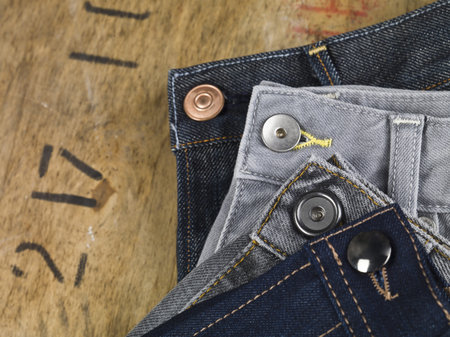 Cropped image of assorted jeans focusing the buttons over the wooden table