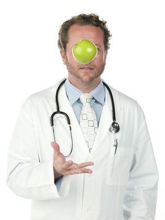 Young doctor tossing a green apple over white background, Model: Derek Gerhardtの写真素材