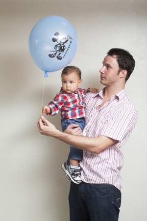 Portrait of father giving a balloon to his son isolated on a backgroundの写真素材