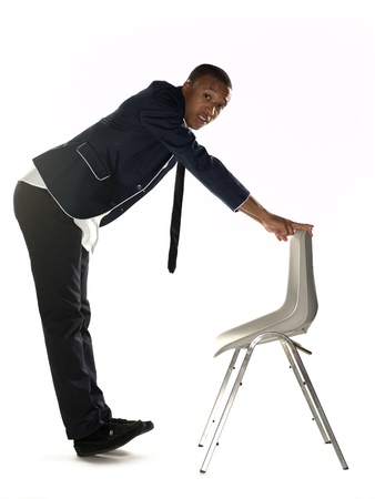 Side view portrait of a businessman standing with chair over white background. Model: Nathaniel Stevensonの写真素材