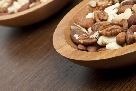 Cropped shot of two wooden bowls of mixed nuts over a wooden tableの写真素材