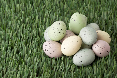 Horizontal image of a group of colorful eggs decorated with black specks laid in green grass