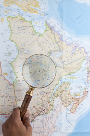 Human hand using a magnifying glass to magnify Quebec in a mapの写真素材