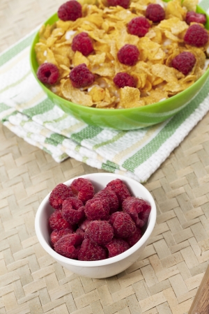 Cornflakes with milk and raspberries on a green bowl isolated onの写真素材