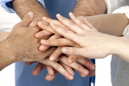 A diverse group of businesspersons with their hands together in form of teamwork and unity