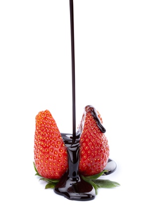 Pouring chocolate sauce between ripe strawberries over the white backgroundの写真素材