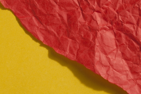 Close up image of ripped crumple red paper against yellow backgroundの写真素材
