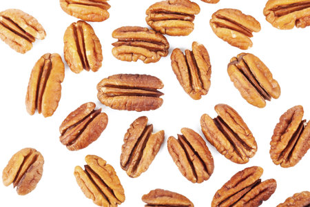 Close-up image of several pecan nuts scattered on a white surface