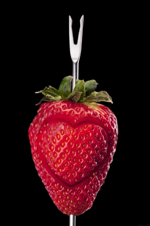 Fresh strawberry with a heart shaped over the black backgroundの写真素材