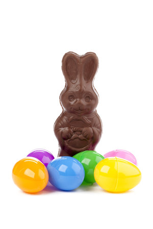 Image of chocolate bunny and colorful eggs against white background