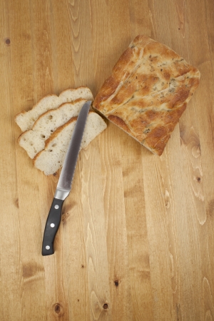 Top view shot of sliced bread loaf and a bread knife over a wooden tableの写真素材